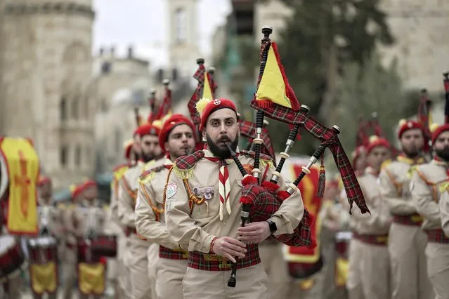 Palestinian scout band members parade through Manger Square at the Church of the Nativity, traditionally believed to be the birthplace of Jesus Christ, during Christmas celebrations, in the West Bank city of Bethlehem, Friday, December 24, 2021. The biblical town of Bethlehem is gearing up for its second straight Christmas Eve hit by the coronavirus with small crowds and gray, gloomy weather dampening celebrations Friday in the traditional birthplace of Jesus. (Photo by Majdi Mohammed/AP Photo)