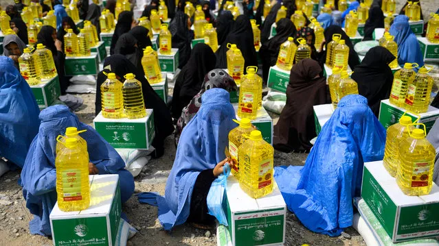 Afghan burqa-clad women sit as they receive aid items by a charity during the holy month of Ramdan in Herat province on May 23, 2019. Muslims throughout the world are marking the month of Ramadan, the holiest month in the Islamic calendar during which devotees fast from dawn till dusk. (Photo by Hoshang Hashimi/AFP Photo)