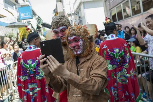 A man playing the role of the Monkey King takes photos with his phone during a Bun Festival parade at Hong Kong's Cheung Chau island, China May 25, 2015. (Photo by Tyrone Siu/Reuters)