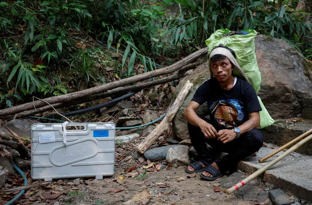 Porters Cornelius Mawa, 28, sits next to an Electronic Voting Machine (EVM), rests on his way to reach a remote polling station, ahead of the first phase of the election, in Shillong in the northeastern state of Meghalaya, India, on April 17, 2024. (Photo by Adnan Abidi/Reuters)