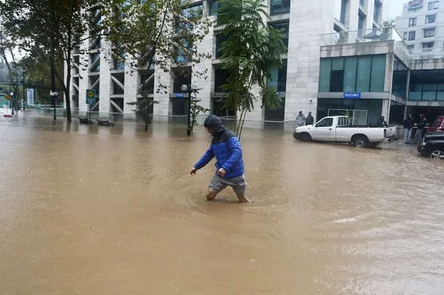 A man crosses a flooded street in Santiago, April 17, 2016. (Photo by Ivan Alvarado/Reuters)