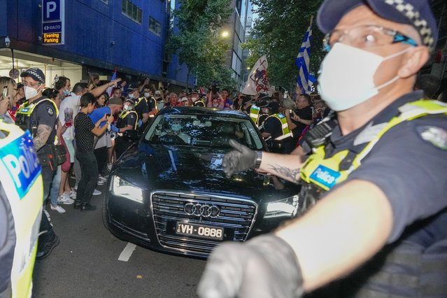 Police clear fans of Serbian Novak Djokovic as a car leaves the offices of lawyers following his court win ahead of the Australian Open in Melbourne, Australia, Monday, January 10, 2022. An Australian judge has reinstated Djokovic's visa, which was canceled after his arrival last week because he is unvaccinated. (Photo by Mark Baker/AP Photo)