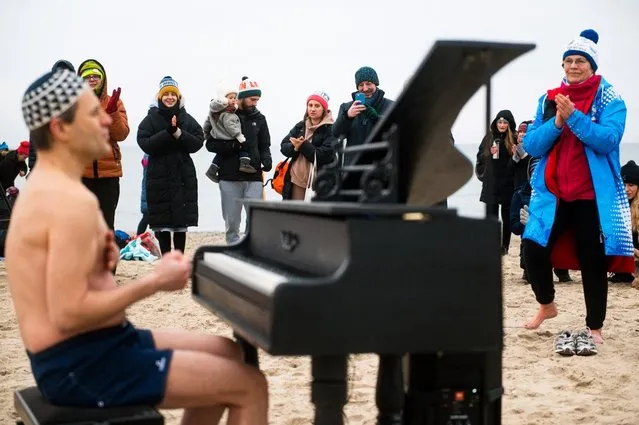 Bystanders applaud for Polish pianist Tomasz Szwelnik, dressed only in swim shorts, as he performs during the charity event “Sea of Angels” for Mikolaj Charuk, a disabled 16-year-old pianist from Gdansk, at the beach in Sopot, Poland, on February 28, 2021. The performance was intended to raise money for the surgery of Mikolaj, who was born without a femur and who collects for his surgery to fully live and develop. The gathered people, accompanied by the piano music, entered the sea for a good cause. (Photo by Mateusz Slodkowski/AFP Photo/Profimedia)