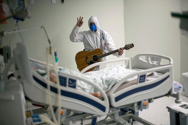 A health worker from the Portuguese charity hospital in Belem, Para State, Brazil, sings and prays for a COVID-19 patient inside the hospital wards and ICU areas as part of Easter celebrations, on April 4, 2021. (Photo by Tarso Sarraf/AFP Photo)
