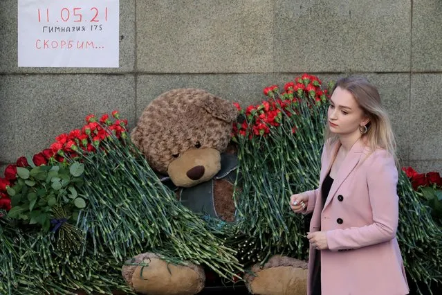 A woman lays flowers at a makeshift memorial outside the representative office of the Republic of Tatarstan to commemorate victims of the deadly shooting in Kazan School Number 175, in Moscow, Russia on May 11, 2021. The placard reads “11.05.2021. School Number 175. We mourn”. (Photo by Evgenia Novozhenina/Reuters)