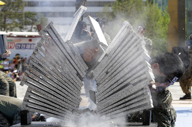 A soldier from the South Korean army special forces breaks stone plates with his hand during a martial arts demonstration for Children's Day at the War Memorial of Korea in Seoul, South Korea, Thursday, May 5, 2016. In South Korea May 5 is celebrated as Children's Day, a national holiday. (Photo by Ahn Young-joon/AP Photo)