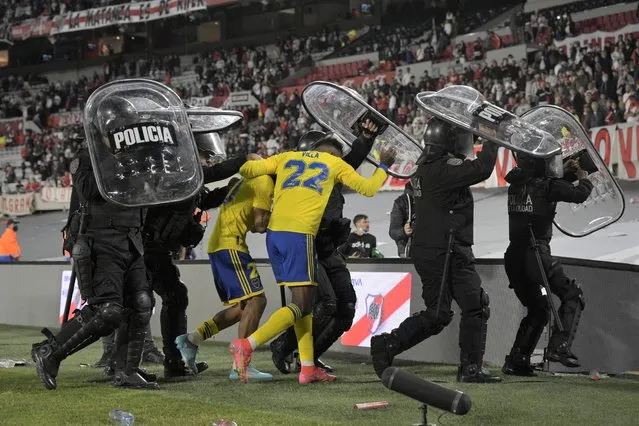 Boca Juniors' Colombian forward Sebastian Villa (22) and midfielder Juan Ramirez leave the field under police shield after defeating River Plater 1-0 in their Argentine Professional Football League match at the Monumental stadium in Buenos Aires, on March 20, 2022. (Photo by Juan Mabromata/AFP Photo)