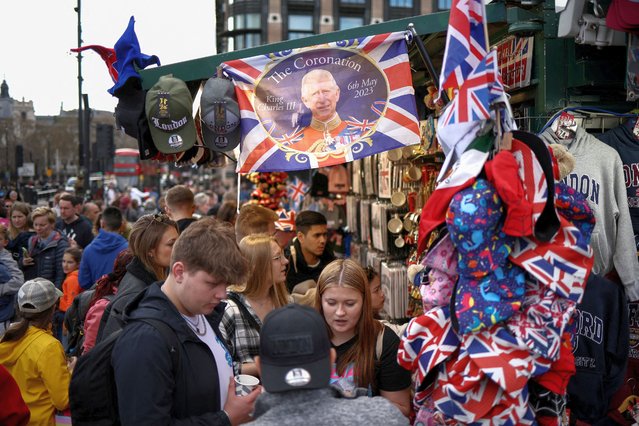 Souvenir merchandise designed for the coronation of King Charles III hang from a kiosk, as people browse souvenir items for sale, outside the Houses of Parliament in London, Britain on April 8, 2023. (Photo by Henry Nicholls/Reuters)