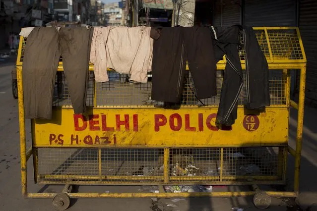 Clothes of migrant workers and other people living in the street are left to dry on a police barricade kept on a roadside in New Delhi, India, Wednesday, July 22, 2015. (Photo by Bernat Armangue/AP Photo)