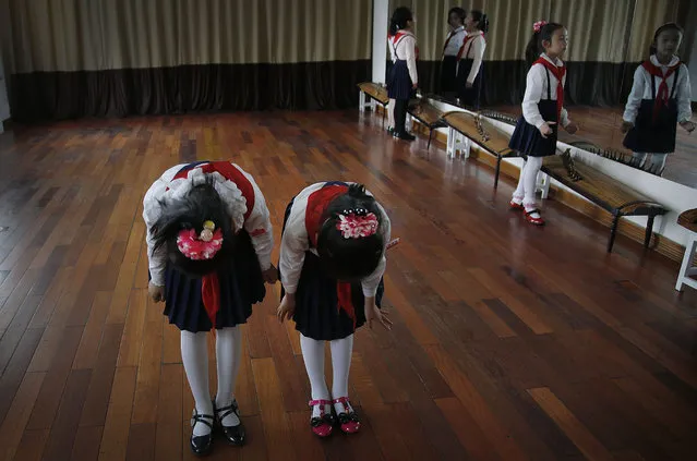 School girls bow after performing a song while others work on their expressions in the mirror during a singing class, Thursday, May 7, 2015, in Pyongyang, North Korea. (Photo by Wong Maye-E/AP Photo)