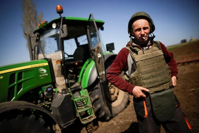 Yuri, a Ukrainian farmer, wearing body armor and helmet, works at the topsoil in a field, amid Russia's invasion of Ukraine, in Zaporizhzhia region, Ukraine on April 26, 2022. (Photo by Ueslei Marcelino/Reuters)