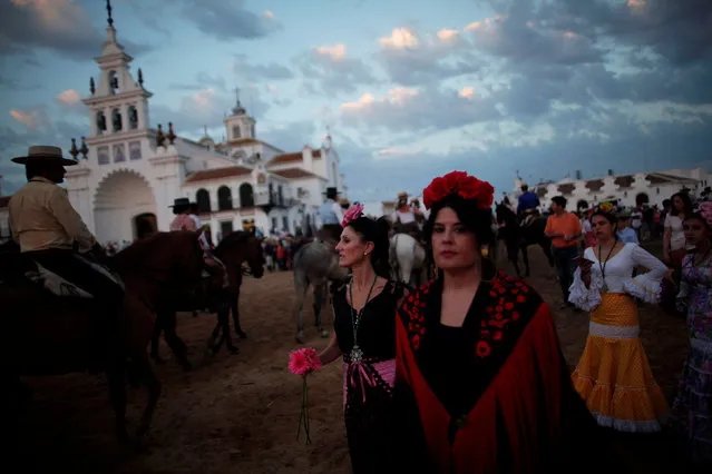 Women look on as pilgrims from the Sanlucar de Barrameda brotherhood ride their horses during a pilgrimage as they arrive at the shrine of El Rocio in Almonte, southern Spain June 2, 2017. (Photo by Jon Nazca/Reuters)