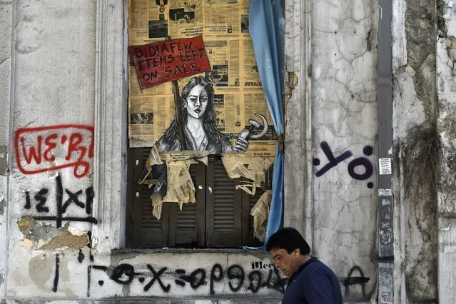 A man walks past a political graffiti in central Athens by artist Bleeps reading' Bid! a few items left on sale' on May 4, 2017 one day after Greece and its creditors closed a troubled chapter on fiscal reforms with a preliminary deal on pension and tax cuts, offering hope for a debt relief agreement later this month . Greece and its creditors on May 3rd closed a troubled chapter on fiscal reforms with a preliminary deal on pension and tax cuts, offering hope for a debt relief agreement later this month. The nation's debt in 2016 stood at nearly 315 billion euros or 179 percent of annual economic output, up from 177.4 percent in 2015. (Photo by Louisa Gouliamaki/AFP Photo)