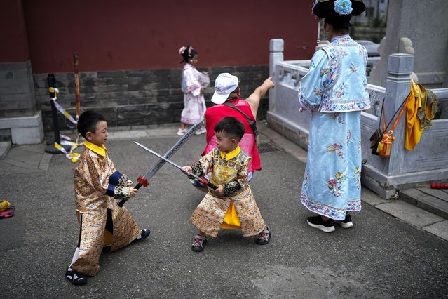 Children dressed in traditional costumes play with toy swords as their family members take souvenir photo outside the Forbidden City during the summer holiday in Beijing, Sunday, August 25, 2024. (Photo by Andy Wong/AP Photo)