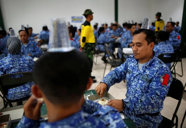 Military trainers make participants of the Bela Negara – “defend the nation” – programme balance plastic cups filled with water on their heads while eating breakfast at a training centre in Rumpin, Bogor, West Java, Indonesia June 2, 2016. (Photo by Darren Whiteside/Reuters)