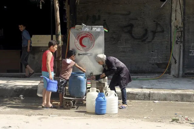 Residents fill containers with water in Aleppo's eastern district of Tariq al-Bab, Syria, August 1, 2015. (Photo by Abdalrhman Ismail/Reuters)