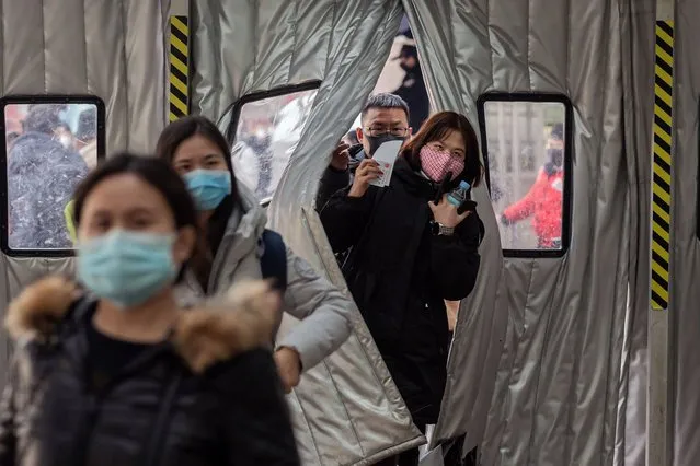 Passengers wearing protective masks walk into Beijing West Railway Station, in Beijing on January 24, 2020. Chinese authorities rapidly expanded a mammoth quarantine effort aimed at containing a deadly contagion on January 24, 2020 to 13 cities and a staggering 41 million people, as nervous residents were checked for fevers and the death toll climbed to 26. (Photo by Nicolas Asfouri/AFP Photo)