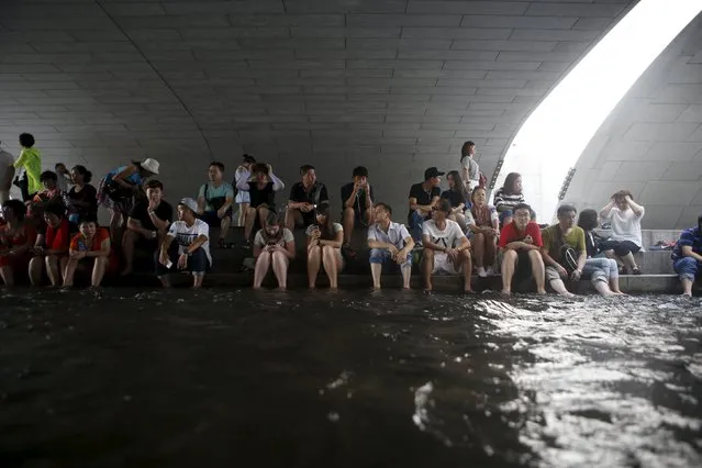 People soak their feet in water to cool down as they sit underneath a bridge at the Cheonggye stream during a hot summer day in Seoul, South Korea, August 12, 2015. (Photo by Kim Hong-Ji/Reuters)