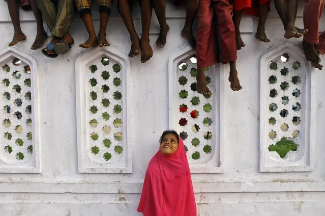 A Muslim girl looks up while some boys sit on a wall, inside the premises of a mosque, as they wait for Iftar (breaking fast) meal during the holy month of Ramadan in the southern Indian city of Chennai July 16, 2014. (Photo by Reuters/Babu)