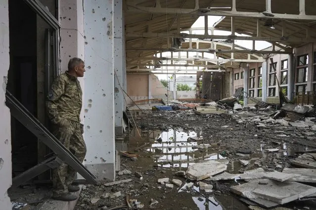 A Ukrainian serviceman looks at the ruins of the sports complex of the National Technical University in Kharkiv, Ukraine, Friday, June 24, 2022, damaged during a night shelling. The building received significant damage. A fire broke out in one part but firefighters managed to put it out. (Photo by Andrii Marienko/AP Photo)