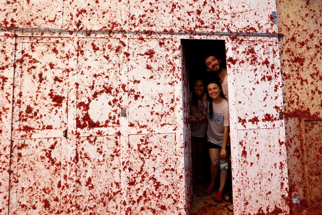 People are photographed inside a house during the annual tomato fight fiesta called “Tomatina” in the village of Bunol near Valencia, Spain, Wednesday, August 30, 2023. Thousands gather in this eastern Spanish town for the annual street tomato battle that leaves the streets and participants drenched in red pulp from 120,000 kilos of tomatoes. (Photo by Alberto Saiz/AP Photo)