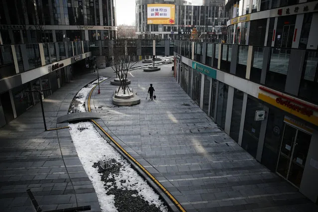 A cleaner walks through a deserted compound of a commercial office building in Beijing, Monday, February 10, 2020. China reported a rise in new virus cases on Monday, possibly denting optimism that its disease control measures like isolating major cities might be working, while Japan reported dozens of new cases aboard a quarantined cruise ship. (Photo by Andy Wong/AP Photo)