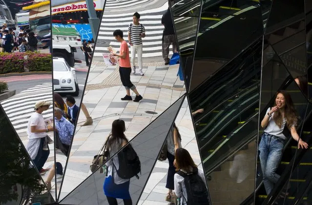 People are reflected in mirrors at an entrance to a department store in the fashion district of Harajuku in Tokyo, May 15, 2015. (Photo by Thomas Peter/Reuters)
