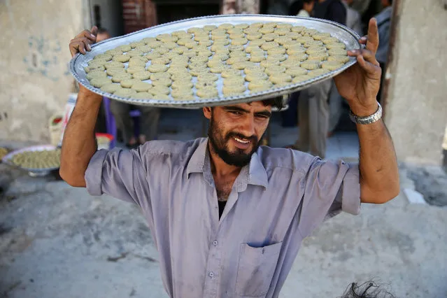 A man carries a tray with traditional sweets on his head ahead of the Eid al-Fitr holiday marking the end of Ramadan in the rebel held besieged town of Douma, eastern Ghouta in Damascus, Syria July 3, 2016. (Photo by Bassam Khabieh/Reuters)
