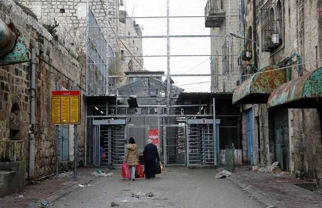 Two Palestinian women approach a checkpoint to cross into the Israeli-controlled Shuhada Street in the divided town of Hebron, in the Israeli occupied West Bank, on January 13, 2020. At the outset of the second Palestinian intifada in 2000, or uprising, the Israeli army declared Shuhada street a “closed military zone”, restricting Palestinian access to residents of the immediate area, on foot only. (Photo by Emmanuel Dunand/AFP Photo)