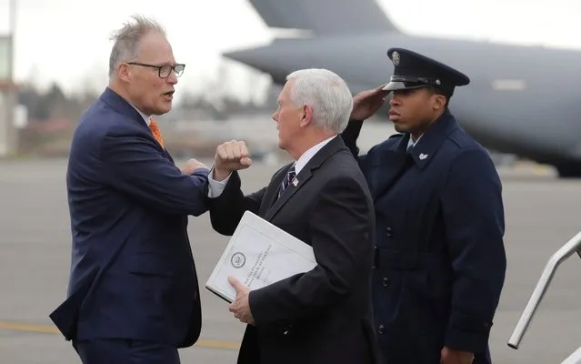Vice President Mike Pence, center, greets Washington Gov. Jay Inslee, left, as Pence arrives, Thursday, March 5, 2020 at Joint Base Lewis-McChord in Washington state. Officials are avoiding handshakes due to the COVID-19 coronavirus. (Photo by Ted S. Warren/AP Photo)