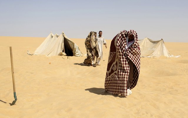 A worker helps patients, who are wrappd in a blanket, leave a “sauna” tent after their sand baths in Siwa, Egypt, August 12, 2015. (Photo by Asmaa Waguih/Reuters)