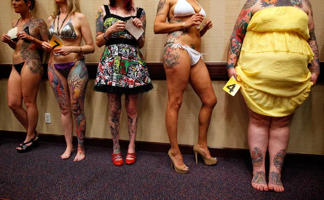 Keisha Holcomb (right), 31, from Fort Collins, Colorado, waits in line to have her tattoos judged in a contest during the National Tattoo Association Convention in Cincinnati, Ohio, on April 13, 2012. Holcomb, the product of a military family upbringing, was 16 when she got her first tattoo and is now a budding tattoo artist herself. She wants to have a full-body tattoo eventually, with the exception of her hands, throat and head. “Try to keep it classy”, she says. (Photo by Larry Downing/Reuters)