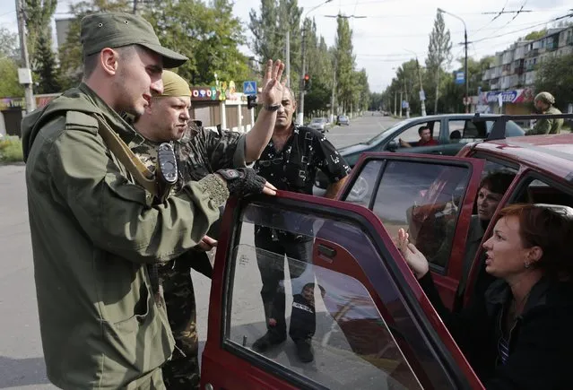 Armed pro-Russian separatists talk to local residents on a street in the settlement of Makiivka, on the outskirts of Donetsk, August 19, 2014. Artillery fire could be heard on Tuesday in Makiivka, on the eastern outskirts of the rebel-controlled city of Donetsk, Reuters reporters at the scene said. (Photo by Maxim Shemetov/Reuters)