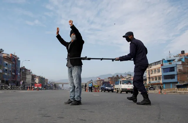 A Nepalese police officer maintains distance as he detains a man defying the lockdown imposed by the government amid concerns about the spread of coronavirus disease (COVID-19), in Kathmandu, Nepal on March 29, 2020. (Photo by Navesh Chitrakar/Reuters)