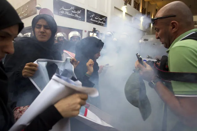 Reuters photographer Ahmed Jadallah and protesters react after police used a flashbang sound grenade during an anti-government rally demanding the release of human rights activist Abdulhadi al-Khawaja in Manama April 18, 2012. (Photo by Darren Whiteside/Reuters)