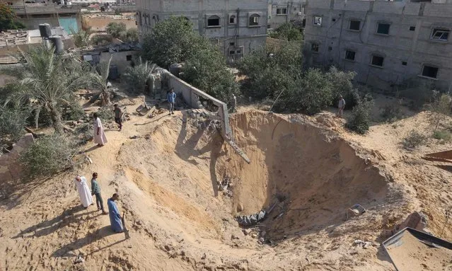Palestinians inspect a crater following the latest three days of conflict with Israel ahead of a truce, in Rafah town in the southern Gaza Strip, on August 8, 2022. (Photo by Said Khatib/AFP Photo)