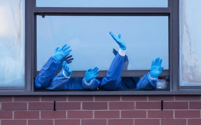 Health workers wearing PPE clap from a window at the Royal Gwent Hospital on April 23, 2020 in Newport, United Kingdom. Following the success of the “Clap for Our Carers” campaign, members of the public are being encouraged to applaud NHS staff and other key workers from their homes at 8pm every Thursday. The Coronavirus (COVID-19) pandemic has infected over 2.5 million people across the world, claiming at least 18,738 lives in the U.K. (Photo by Matthew Horwood/Getty Images)