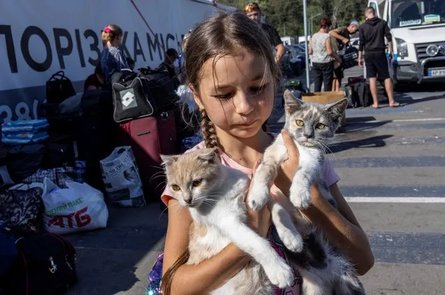 9-year Anastasija Maksimova holds her cats as she waits with her family at the relief centre, where volunteers provide food and transportation for those who are not travelling on their own, to be transferred to other parts of the country, amid Russia's invasion of Ukraine, in Zaporizhzhia, Ukraine on August 29, 2022. (Photo by Umit Bektas/Reuters)