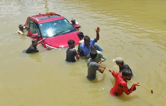 People pull a car through a water-logged road following torrential rains in Bengaluru, India on September 5, 2022. (Photo by Reuters/Stringer)