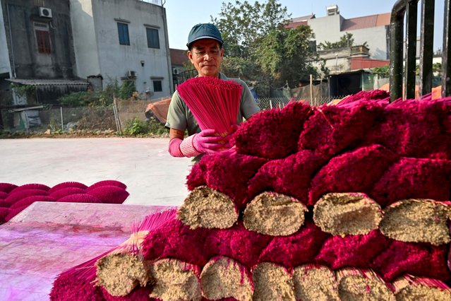A worker arranges dried incense sticks to dry in a courtyard in Quang Phu Cau village on the outskirts of Hanoi on January 21, 2025, ahead of Lunar New Year celebrations, known in Vietnam as Tet. (Photo by Nhac Nguyen/AFP Photo)