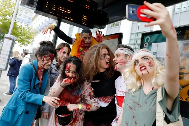 People wearing costumes pose for a “selfie” photograph as they gather at a bus stop before participating in a “Zombie Walk” on World Zombie Day, in London on October 7, 2017. (Photo by Tolga Akmen/AFP Photo)