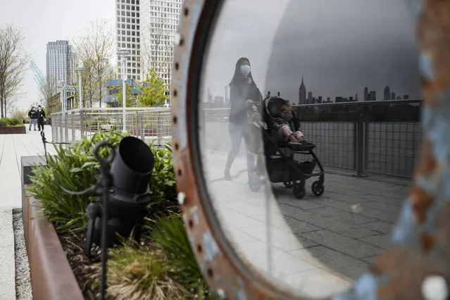 A visitor pushes a stroller while wearing a protective mask at Domino Park, Friday, May 8, 2020, in the Brooklyn borough of New York. Some parks will see stepped-up policing to stem the spread of the coronavirus, New York City Mayor Bill de Blasio said Friday. He also announced that 2,500 members of a “test and trace corps” will be in place by early June to combat the virus. (Photo by John Minchillo/AP Photo)