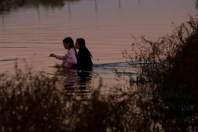 Estephania Mendez, a nine-months pregnant Mexican migrant, is assisted by a friend in crossing the Rio Bravo river, the border between the United States and Mexico, with the intention of turning themselves in to U.S. Border Patrol agents to seek asylum, seen from Ciudad Juarez, Mexico on January 3, 2024. (Photo by Jose Luis Gonzalez/Reuters)