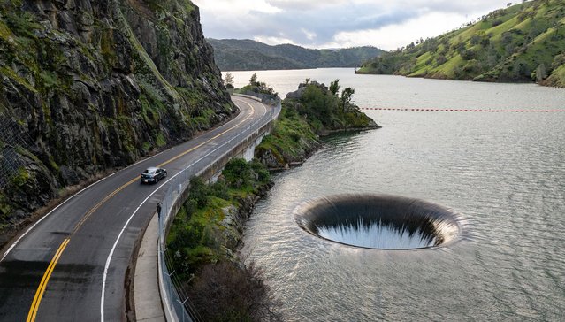 In this aerial photograph the Morning Glory spillway at Lake Berryesa is seen dropping water down a vertical spillway into Putah Creek in Napa, California, on March 14, 2025. This spillway has become affectionately known by Northern Californians as the “Glory Hole”. The circular drain is 72 feet in diameter and sends overflow water 200ft straight down through a large tunnel and eventually downstream to control water levels at the Monticello Dam. (Photo by Josh Edelson/AFP Photo)