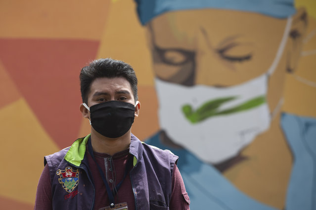 Urban artist Kevin Perez poses for photos in front of his mural in honor of health workers who assist COVID-19 patients in the country's hospitals, near La Verbena cemetery in Guatemala City, Wednesday, June 24, 2020. (Photo by Moises Castillo/AP Photo)