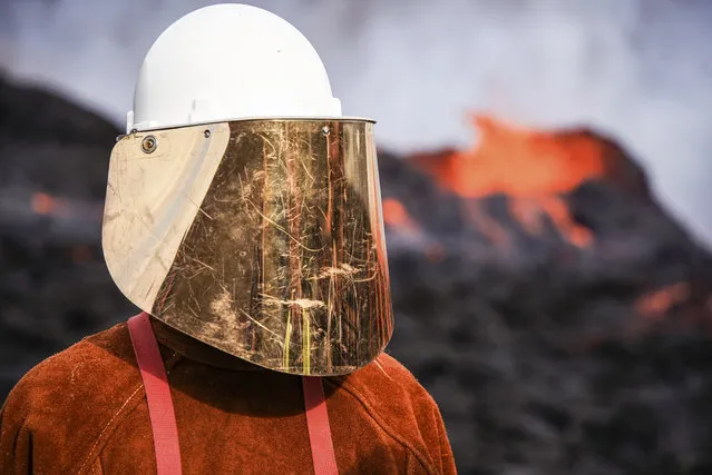 A person wears protective gear as they stand close to the lava flowing from Fagradalsfjall volcano in Iceland on Wednesday August 3, 2022, which is located 32 kilometers (20 miles) southwest of the capital of Reykjavik and close to the international Keflavik Airport. (Photo by Marco Di Marco/AP Photo)