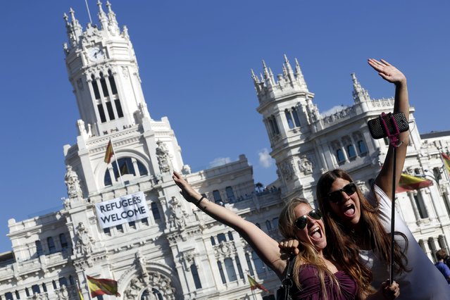 Two women take a selfie outside Madrid's Town Hall, where a banner welcoming refugees is displayed, in Madrid, Spain, September 8, 2015. (Photo by Susana Vera/Reuters)