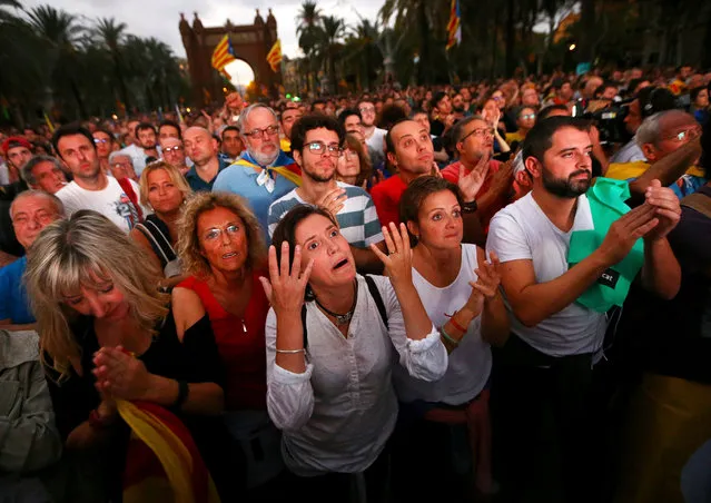 People react as they watch a sesion of the Catalonian regional parliament on a giant screen at a pro-independence rally in Barcelona, Spain, October 10, 2017. (Photo by Ivan Alvarado/Reuters)