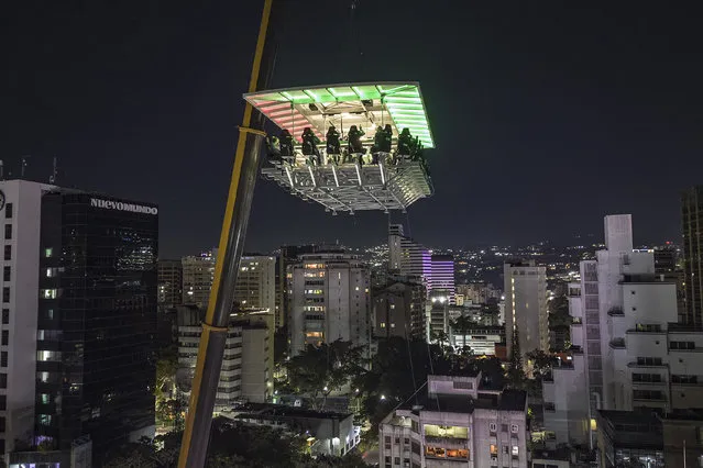 People dine in the air at the Altum restaurant in Caracas, Venezuela, late Thursday, December 22, 2022. Altum, the “restaurant in the heights”, is for 25 diners that is elevated by a crane to 50 meters (164 feet). (Photo by Matias Delacroix/AP Photo)