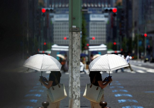 A woman holding a parasol walks on the street, in Tokyo, Japan on July 8, 2025. (Photo by Issei Kato/Reuters)